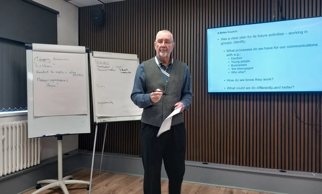 A trainer standing beside flip charts and a presentation screen