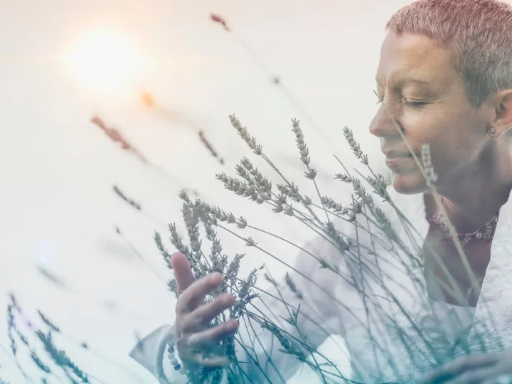 Woman holding plant against sky