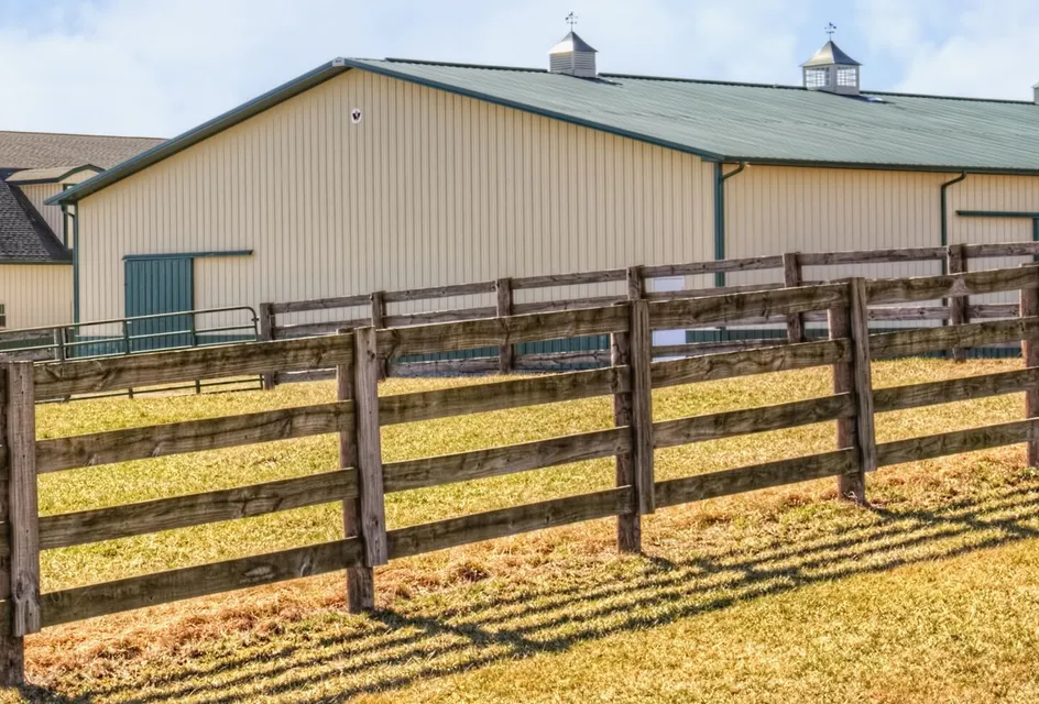 Farm barn with cream walls behind a fence