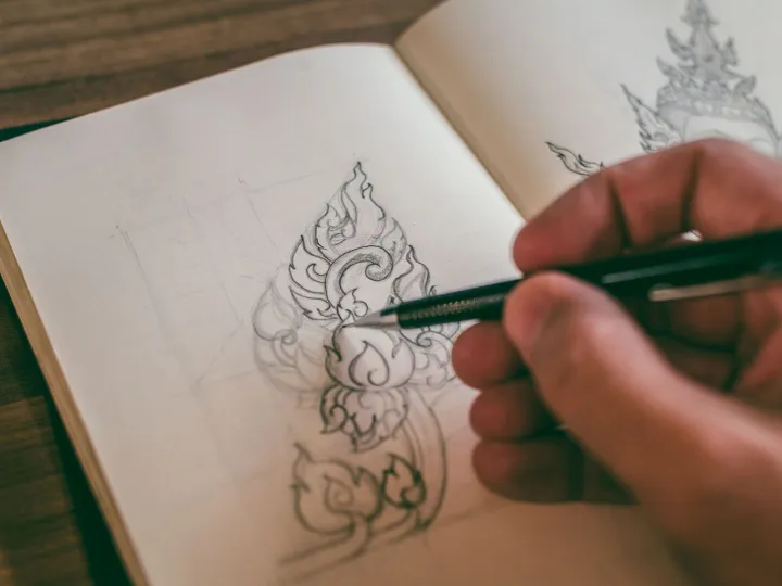 A designer sketching detailed drawings in a notebook