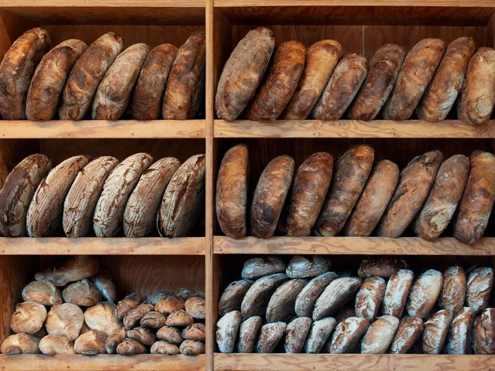 A variety of artisanal breads neatly arranged on wooden shel