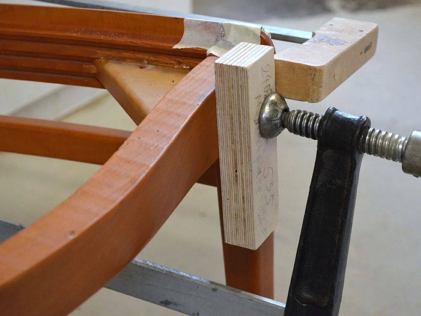 Carpenter's clamp holding a bespoke wooden chair frame in a joinery workshop