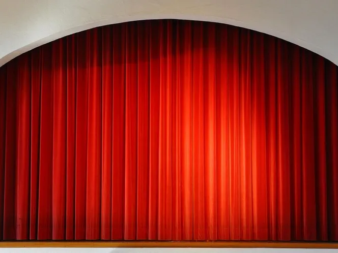 Red curtains drawn across a small church hall stage