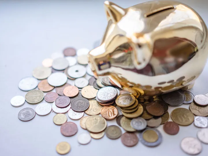 A golden piggy bank surrounded by assorted coins