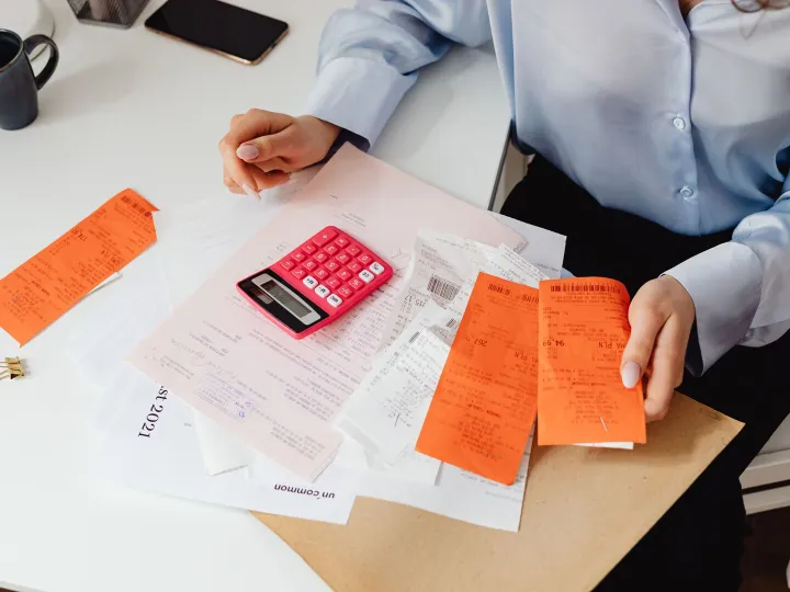 A small business owner working through receipts and bills with a calculator