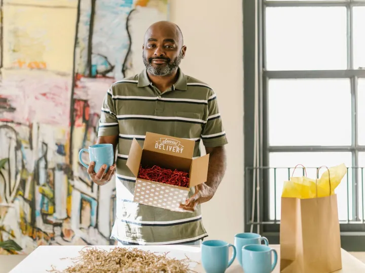 A small business owner packing coffee mugs into a delivery box