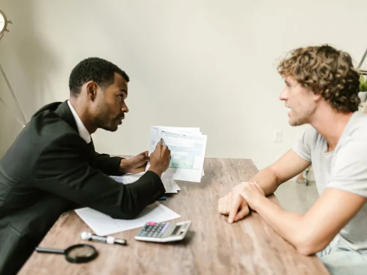 An accountant going through financial paperwork with a client at a desk