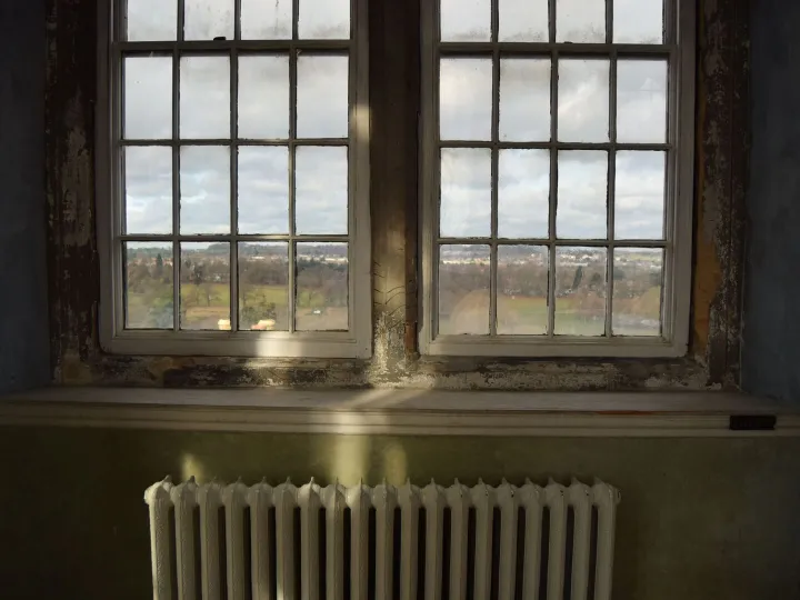 An old white radiator beneath a tall church window in winter light
