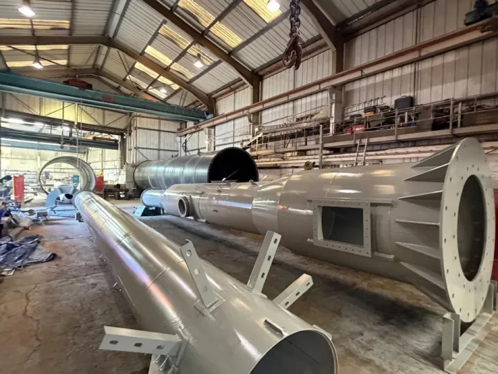 Several topcoated gloss grey steel chimney sections laid out across a workshop floor