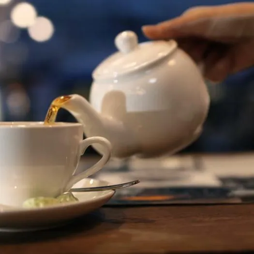 close-up-shot-of-female-hand-pouring-black-hot-tea-from-the-pot-into-the-cup_xk8fqbyb__F0000