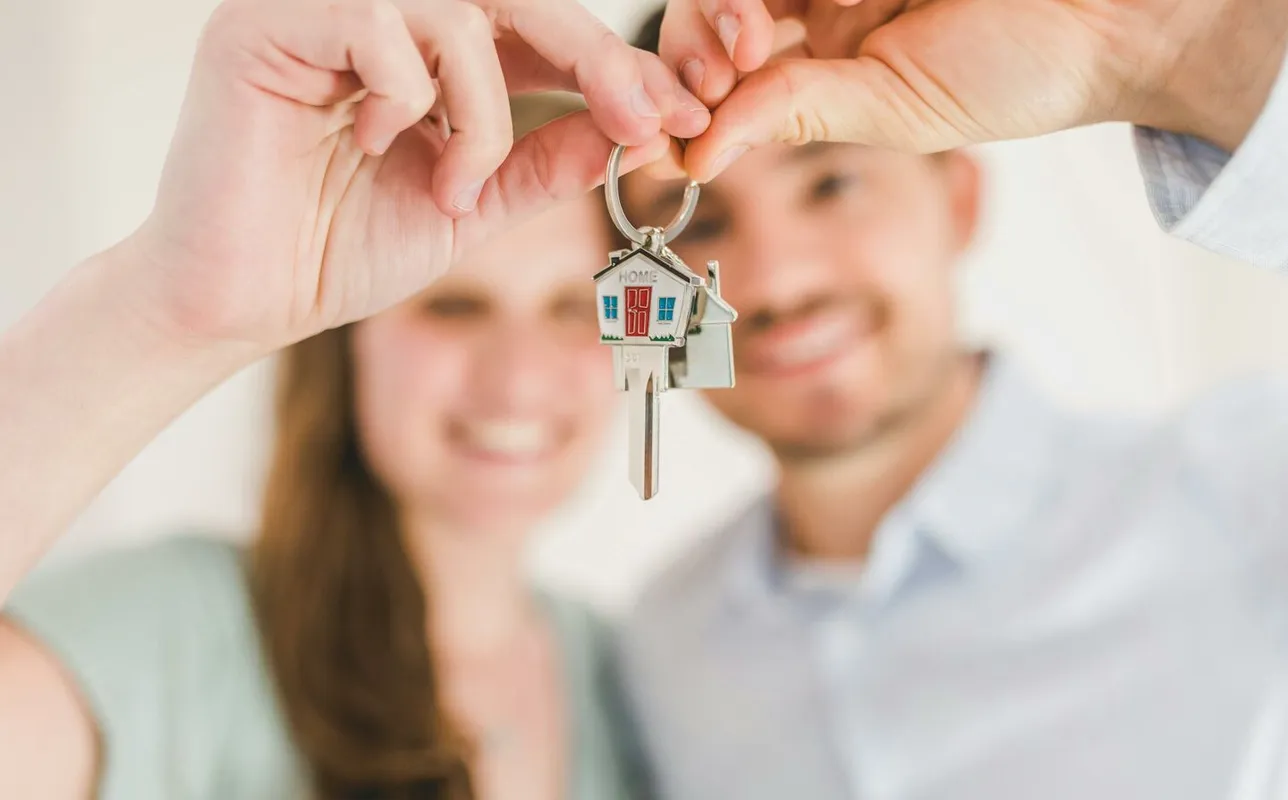 Young couple holding keys to their new home, symbolizing a fresh start and investment in real estate.