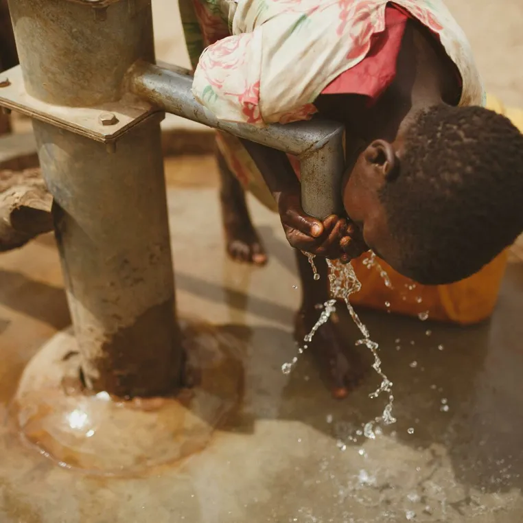 A girl bends to drink clean water from a well in Kitgum, Northern Uganda.
