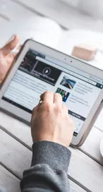A man uses a tablet to browse news while enjoying