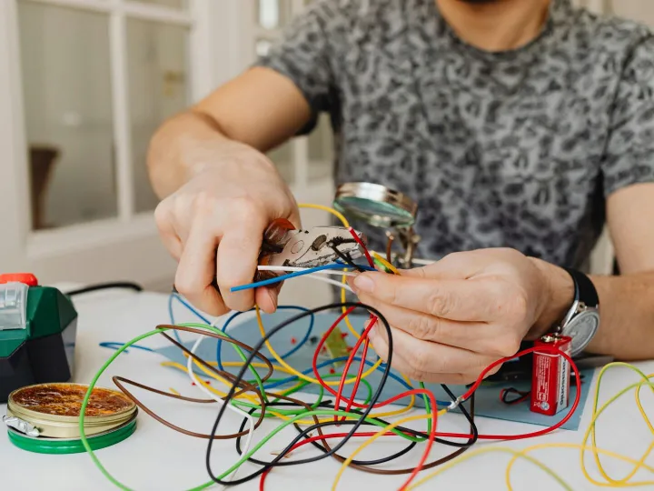Person using pliers to cut through colorful electr