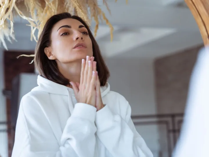 Young woman at home in the bedroom in a warm white hoodie po
