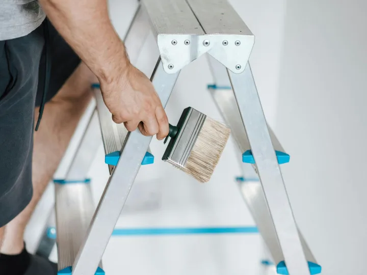 Close-up of a painter on a ladder holding a wide