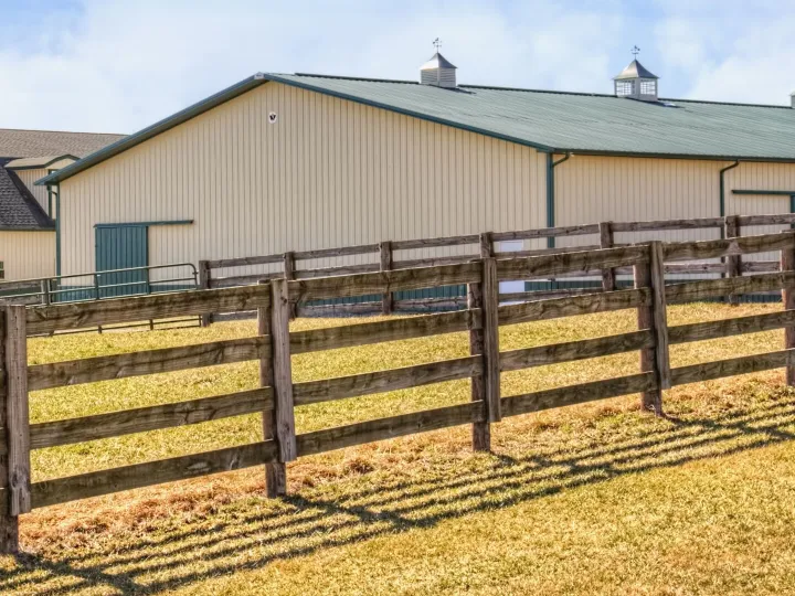Farm barn with cream walls behind a fence