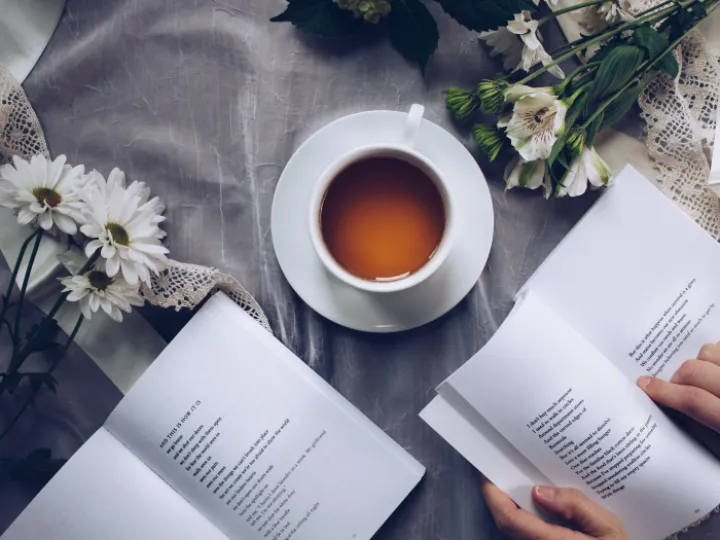 White Ceramic Teacup With Saucer Near Two Books Above Gray Floral Textile