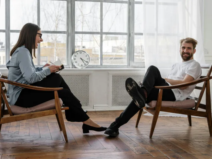 2 Women Sitting on Brown Wooden Chair