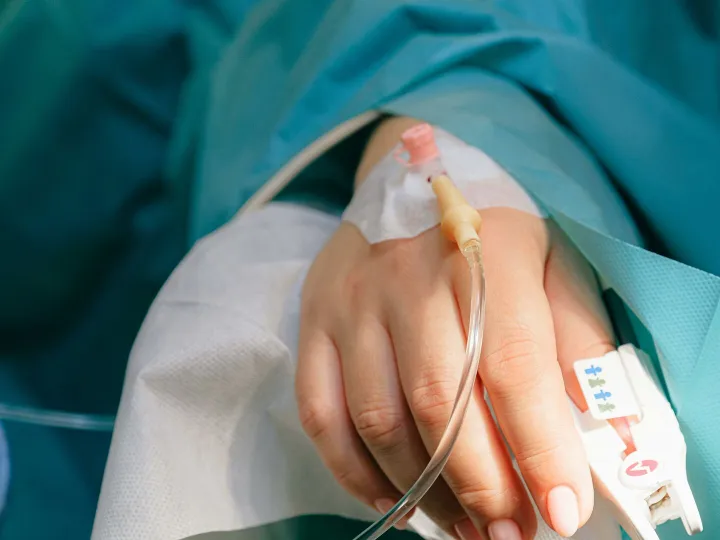 Close-up of a patient's hand with intravenous therapy and pulse oximeter, symbolizing healthcare and treatment.