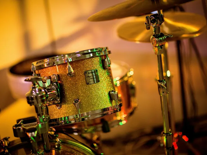 A vibrant close-up photo of a glittery drum set under concert lights, evoking a lively music performance.