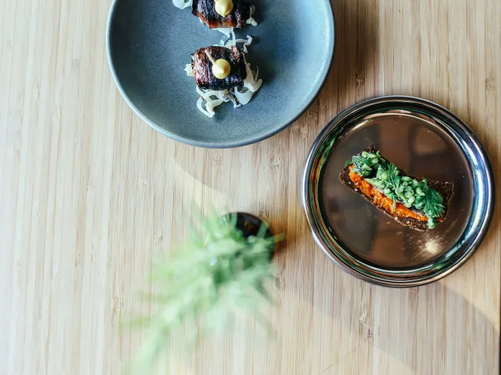 Elegant plating of gourmet dishes on wooden table, showcasing fine dining artistry.