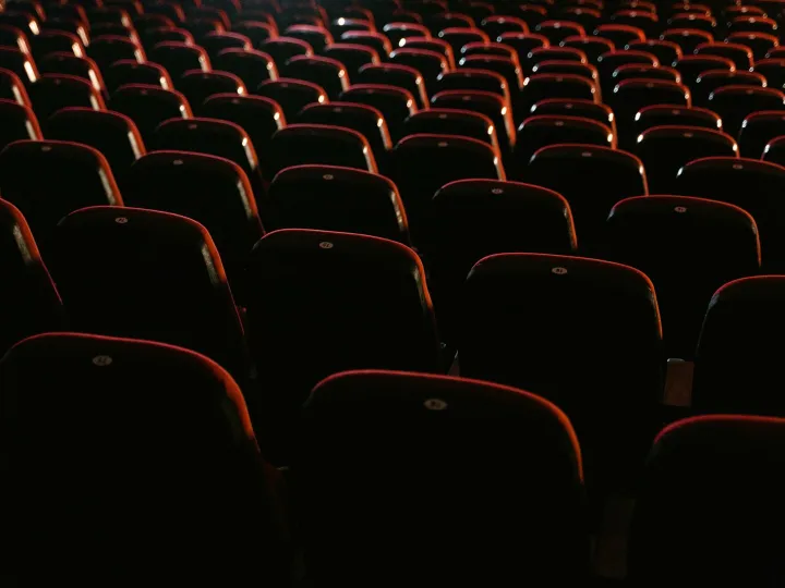 Rows of empty red seats in a dimly lit movie theater, showcasing a cinema environment.