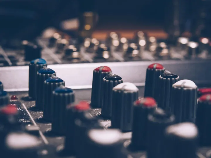 Close-up of audio mixer knobs in a dimly lit studi