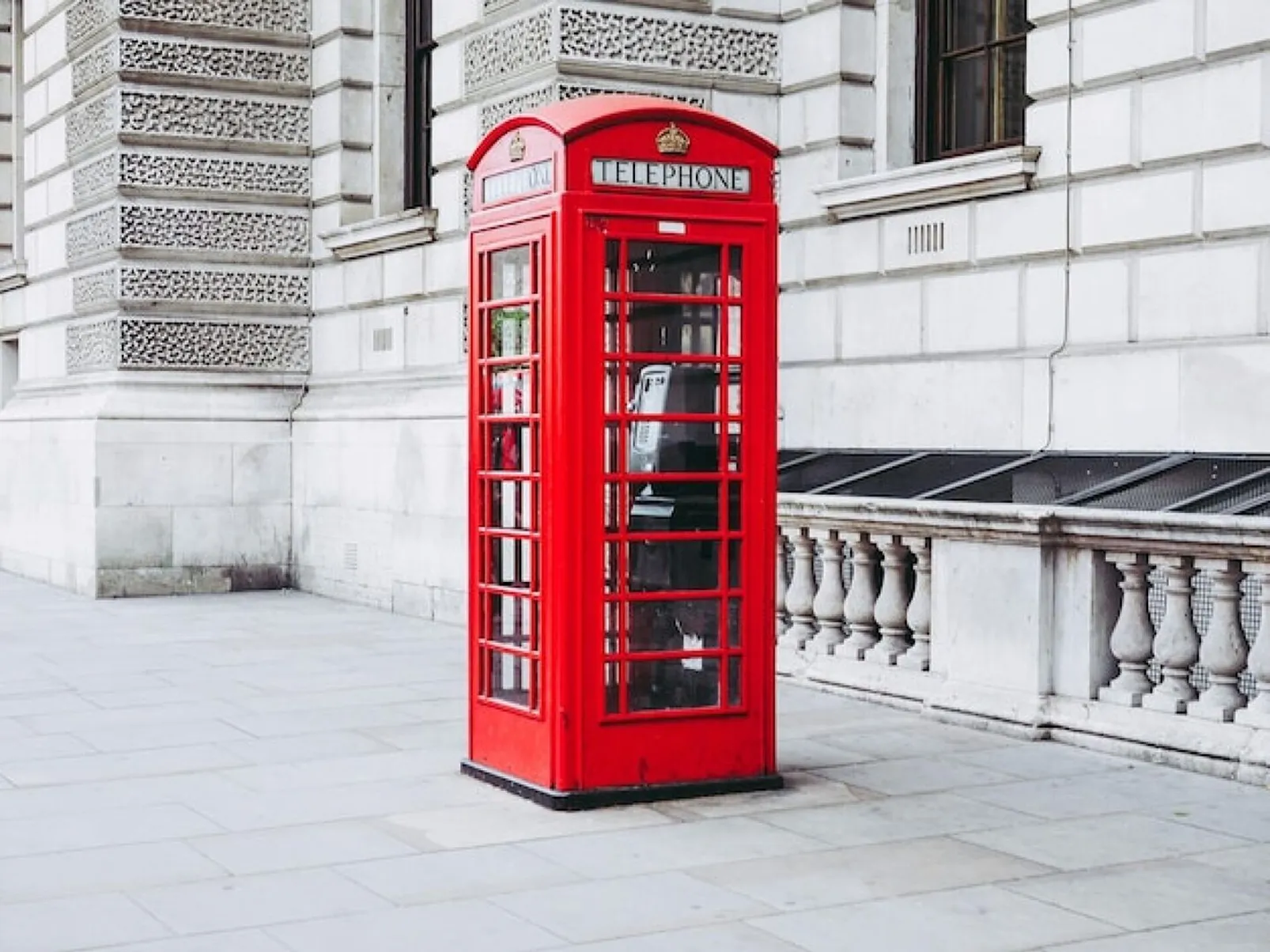 Red telephone booth on sidewalk against building