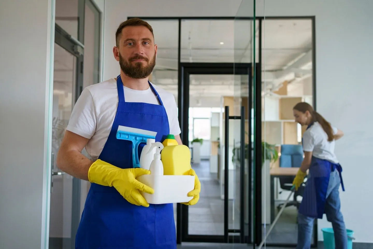 Cleaner with squeegee and supplies in a hallway
