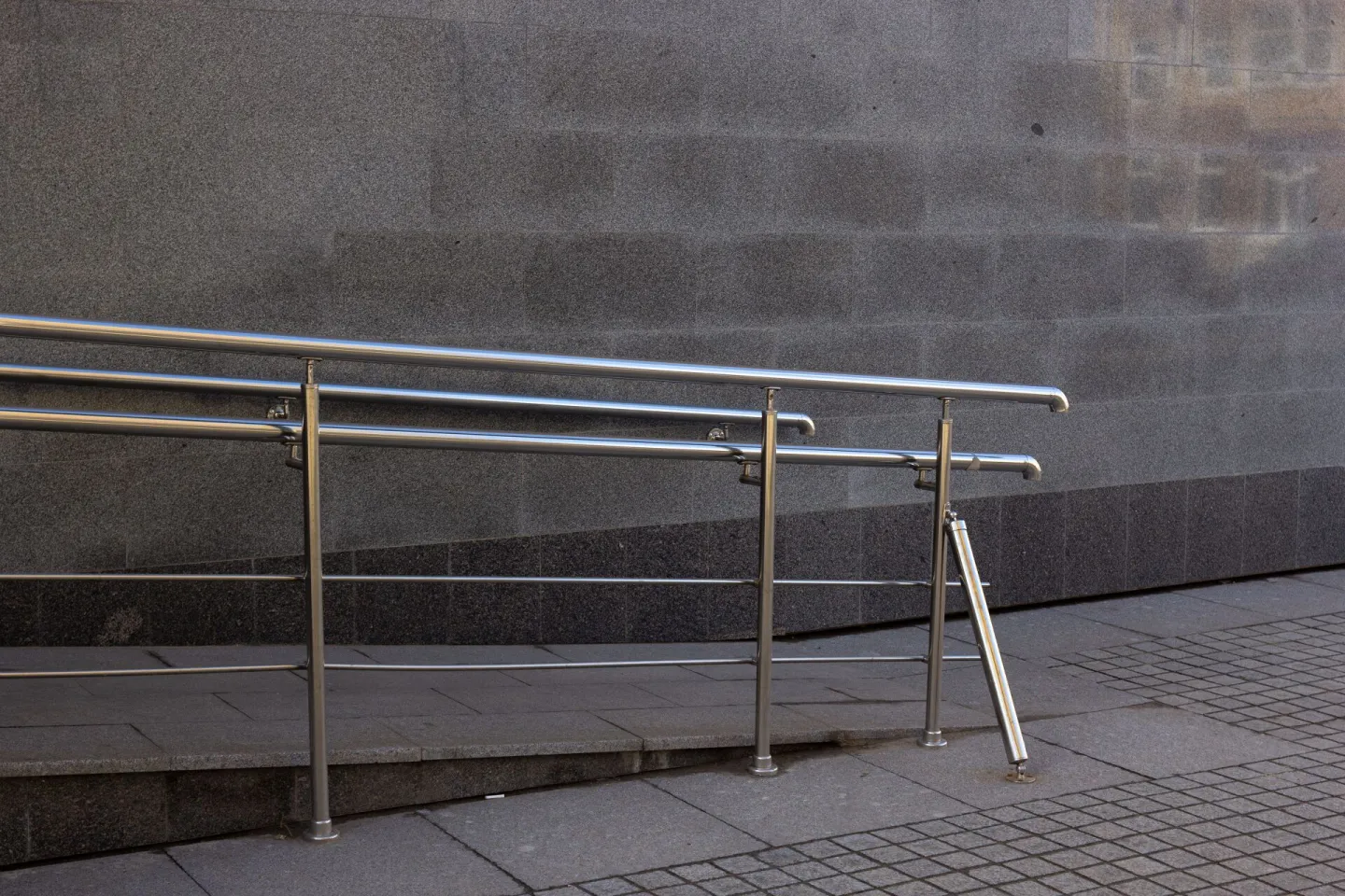 Close-up of a metal handrail and concrete ramp