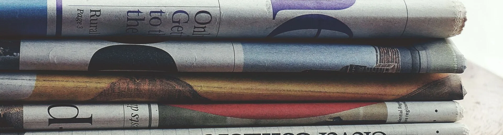 A stack of folded newspapers placed on a wooden