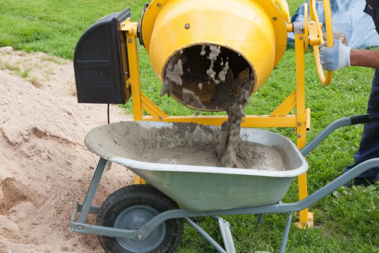 Worker fills cement concrete mixer