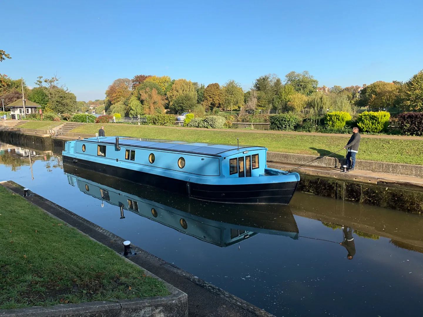 Blue solar-powered boat sailing on a canal waterway