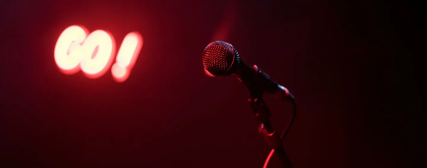 Microphone on stage with glowing red 'GO!' sign, perfect for nightlife themes.