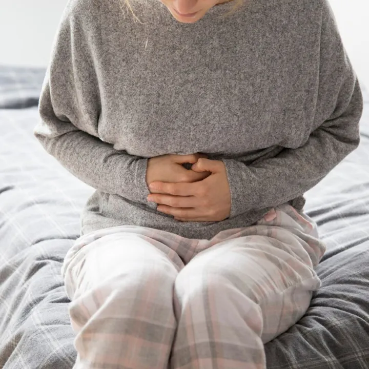 Sick woman with hands on stomach suffering from