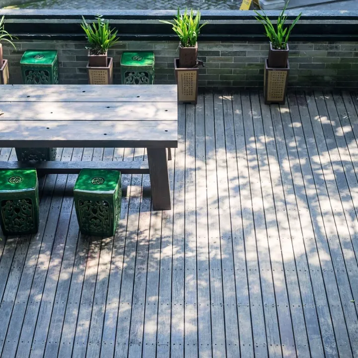 Timber deck seating area with a wooden table, ceramic stools and potted plants