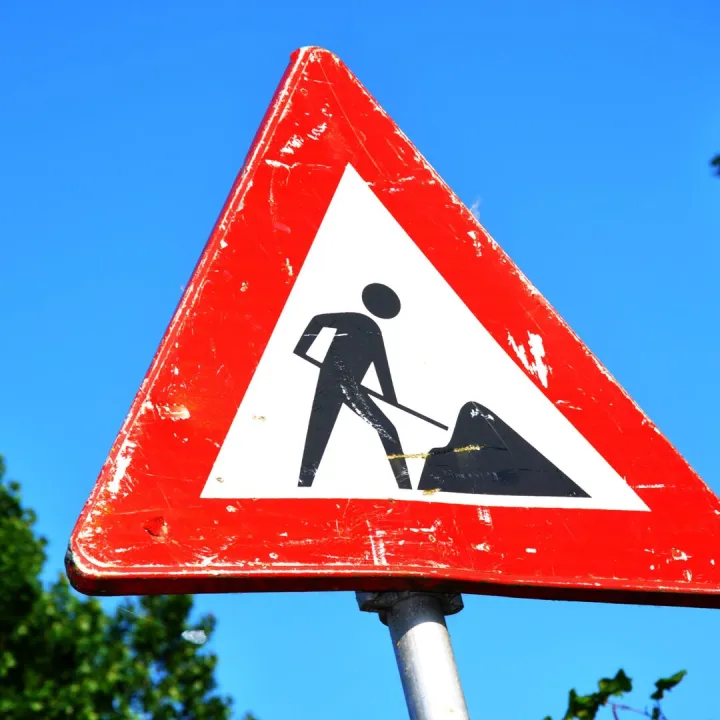 A red and white roadwork warning sign with a