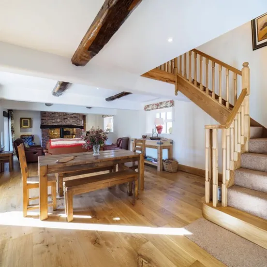 The dining area at Otters Retreat with a table seating eight and the oak staircase beyond