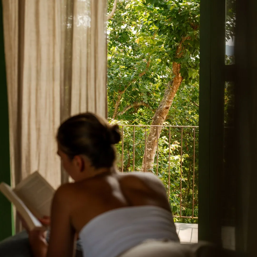 A guest reading beside the open window of the 360 View Suite at Peacock Hill Sigiriya