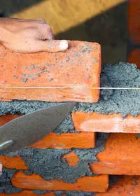 Builder laying a course of bricks with a trowel and string line