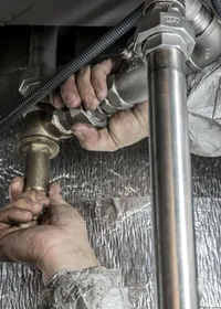 Plumber tightening a pipe fitting under a sink