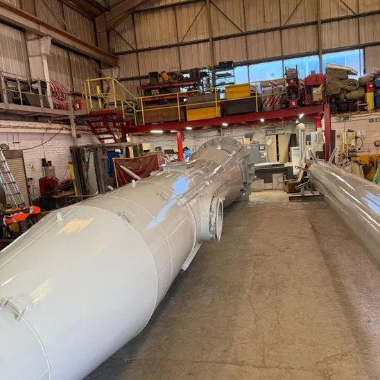 Topcoated gloss grey steel chimney sections lying on the floor of a workshop