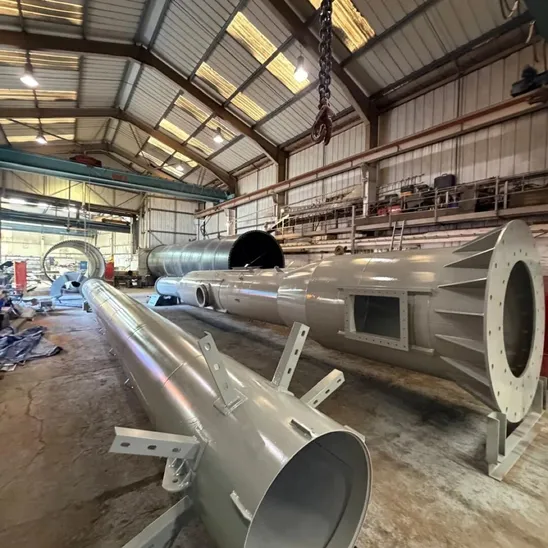Several topcoated gloss grey steel chimney sections laid out across a workshop floor