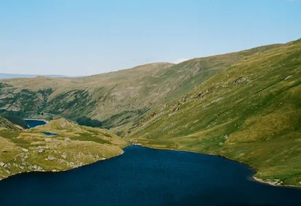 Aerial view of a tranquil lake surrounded by rolling hills in England's Lake District.