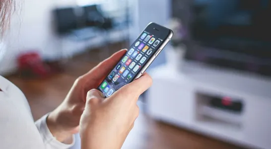 Woman browsing smartphone indoors, highlighting modern technology and communication in a cozy home setting.