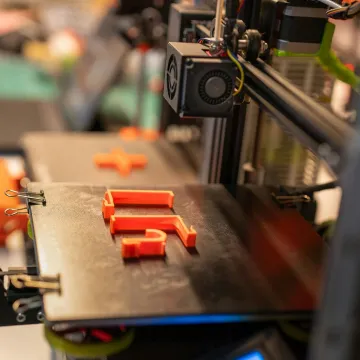 Detailed view of a 3D printer creating an orange p