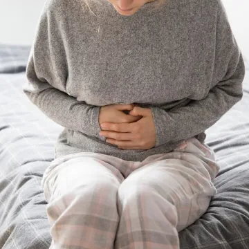 Sick woman with hands on stomach suffering from