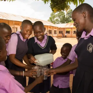 Children at St Balikuddembe school enjoying water from their new tank – Copyright All We Can
