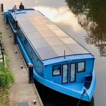 Blue solar-powered electric boat moored up to the shore